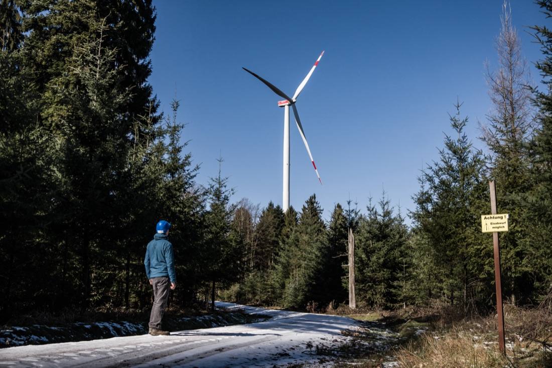 Windenergieanlage über bewaldetem Höhenzug